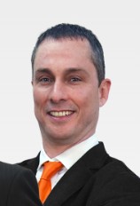 CEO Kris Barksdale smiling in suit and orange tie