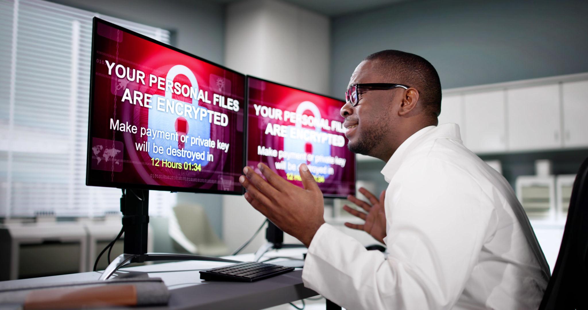 Man reacts to ransomware demand on dual monitors in office