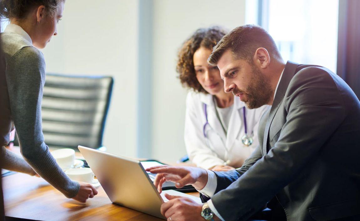 Healthcare professionals collaborating on laptop in office setting